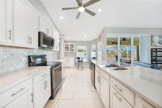 kitchen featuring appliances with stainless steel finishes, a sink, a ceiling fan, tasteful backsplash, and white cabinetry
