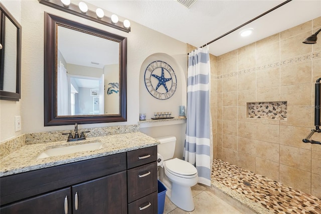 full bathroom with a stall shower, toilet, vanity, and tile patterned floors