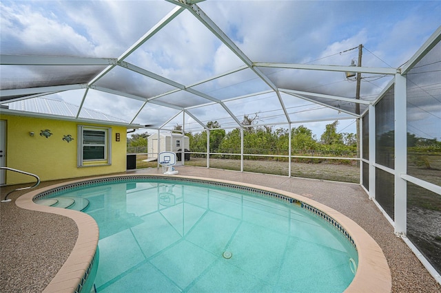 outdoor pool with a shed, a lanai, and a patio