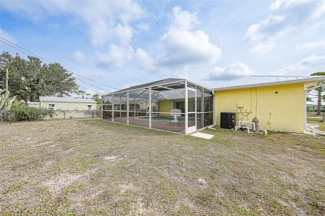 back of house featuring stucco siding, an outdoor pool, glass enclosure, and metal roof