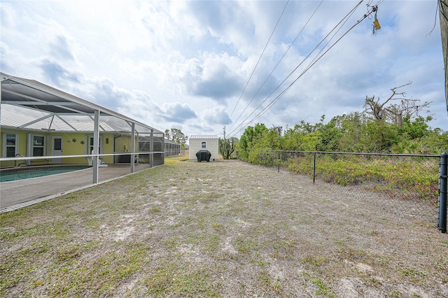 view of yard featuring fence and glass enclosure