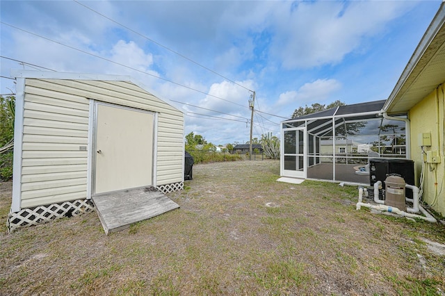 view of grassy yard with a storage unit, an outdoor structure, and a lanai