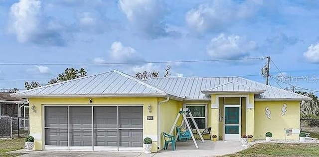 ranch-style home with an attached garage, stucco siding, driveway, and metal roof