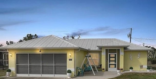 view of front of home with a garage, stucco siding, metal roof, and concrete driveway