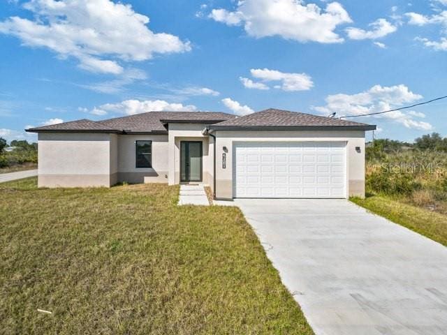 prairie-style home featuring concrete driveway, a garage, a front yard, and stucco siding
