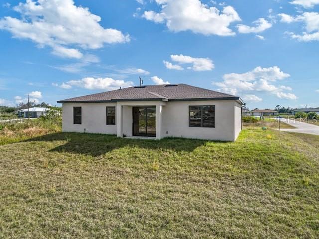 rear view of house with a lawn and stucco siding