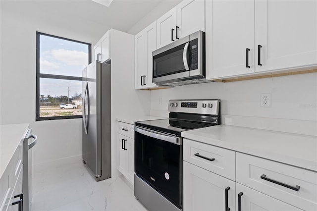 kitchen with light countertops, white cabinetry, appliances with stainless steel finishes, and marble finish floor
