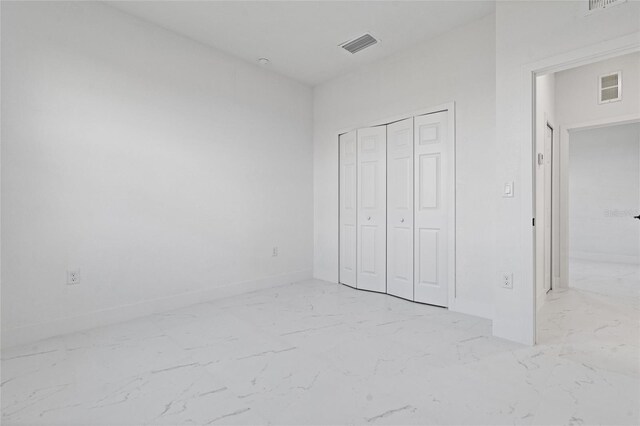 unfurnished bedroom featuring baseboards, visible vents, marble finish floor, and a closet