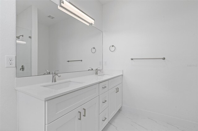 full bath with double vanity, baseboards, a sink, and marble finish floor