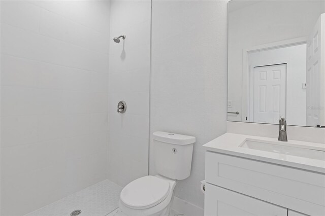bathroom with vanity, a tile shower, and toilet