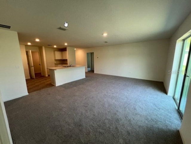 unfurnished living room featuring recessed lighting, visible vents, a sink, and carpet