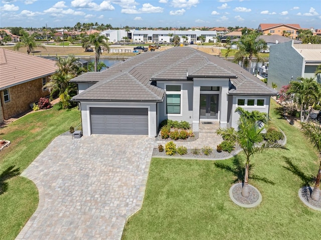 view of front facade featuring a garage, a residential view, driveway, and a front yard
