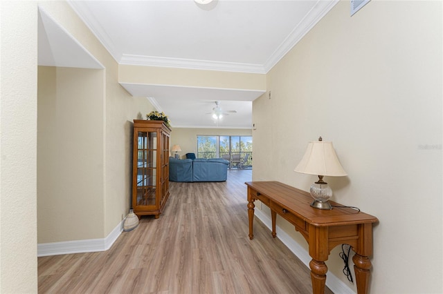 hallway with crown molding, baseboards, and light wood finished floors