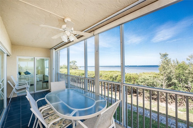 sunroom / solarium featuring a water view and ceiling fan