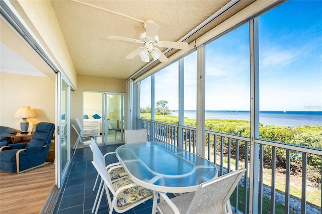 sunroom / solarium featuring outdoor dining space, a water view, and a ceiling fan