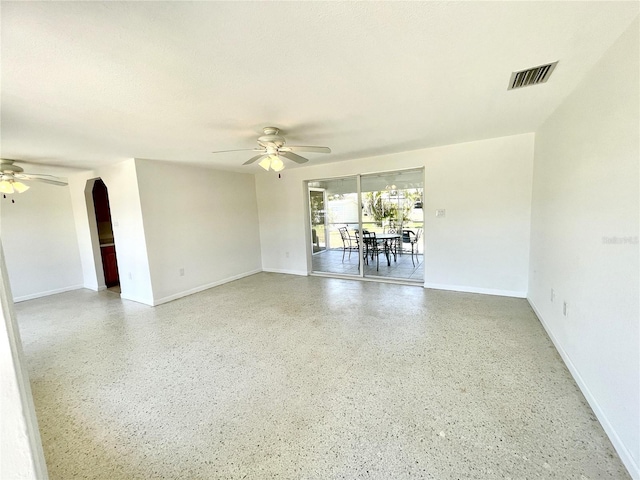 spare room with baseboards, a ceiling fan, visible vents, and light speckled floor