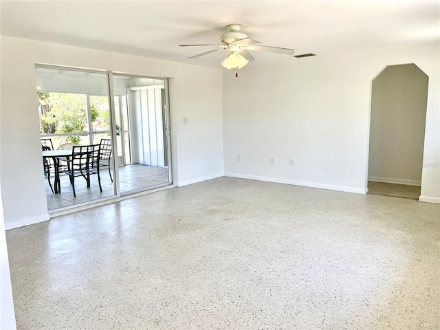 unfurnished room featuring speckled floor, visible vents, baseboards, and a ceiling fan