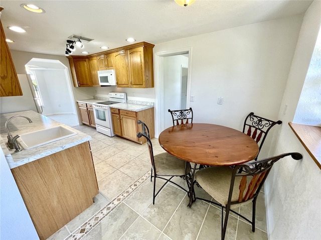kitchen with recessed lighting, white appliances, a sink, brown cabinets, and light countertops