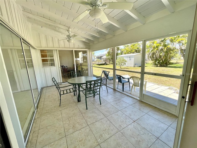 sunroom with a ceiling fan and beam ceiling