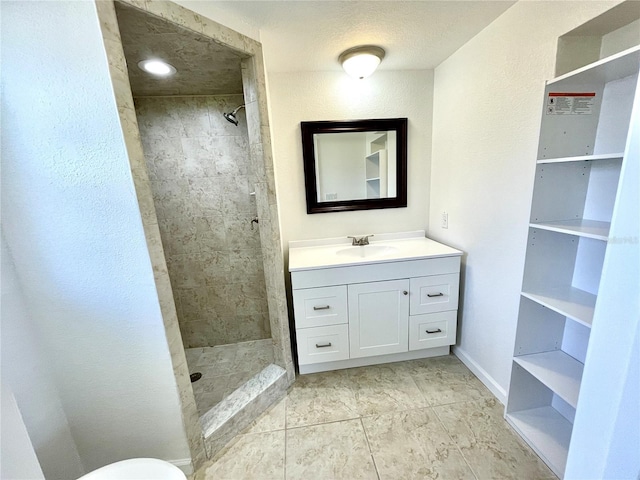 bathroom with vanity, baseboards, and tiled shower