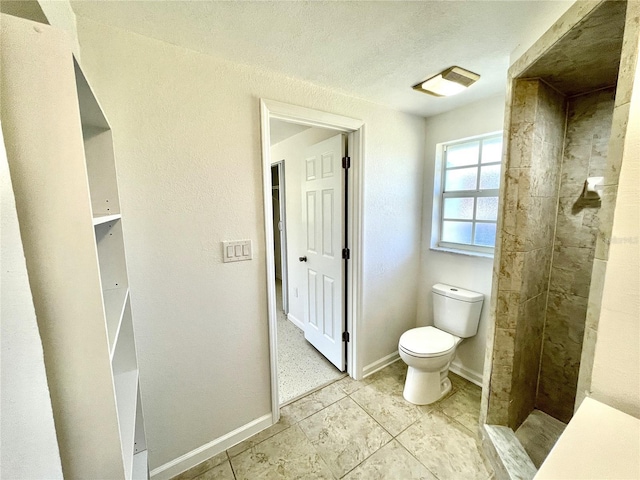 full bath featuring toilet, baseboards, and tiled shower