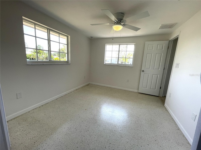 unfurnished bedroom featuring baseboards, ceiling fan, visible vents, and speckled floor