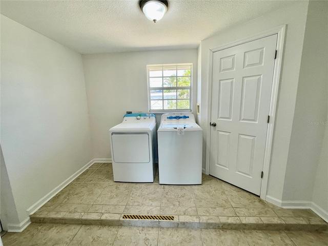 laundry area featuring baseboards, laundry area, separate washer and dryer, and a textured ceiling