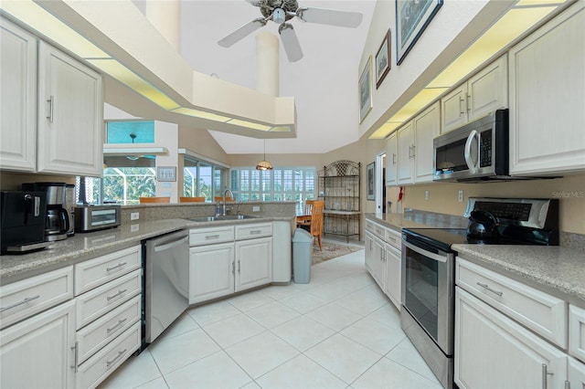 kitchen featuring a peninsula, light tile patterned flooring, light countertops, a sink, and appliances with stainless steel finishes