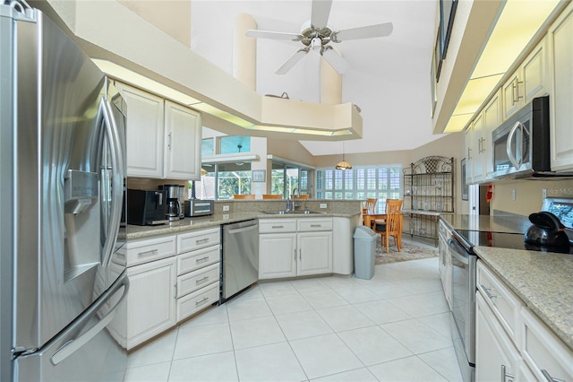 kitchen with a sink, high vaulted ceiling, stainless steel appliances, a ceiling fan, and a peninsula