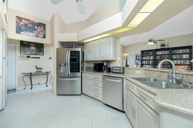 kitchen with ceiling fan, a sink, light tile patterned floors, light stone counters, and stainless steel appliances