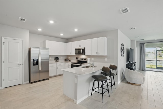 16079 Bandermill Dr, Port Charlotte, FL 33953 - kitchen with stainless steel appliances, a sink, light wood finished floors, a peninsula, and white cabinets