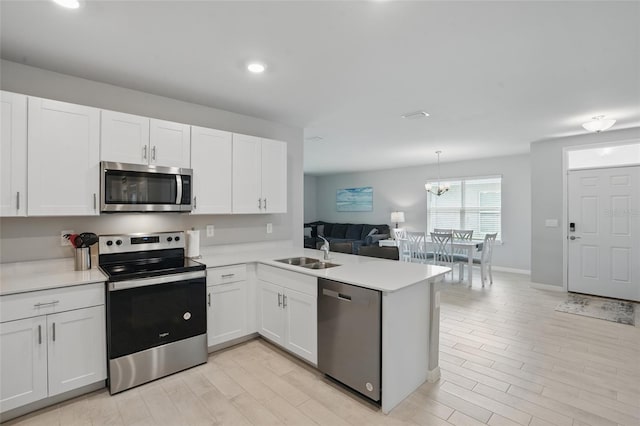 16079 Bandermill Dr, Port Charlotte, FL 33953 - kitchen with appliances with stainless steel finishes, a sink, a peninsula, light countertops, and light wood-type flooring