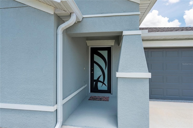 property entrance with stucco siding and a garage