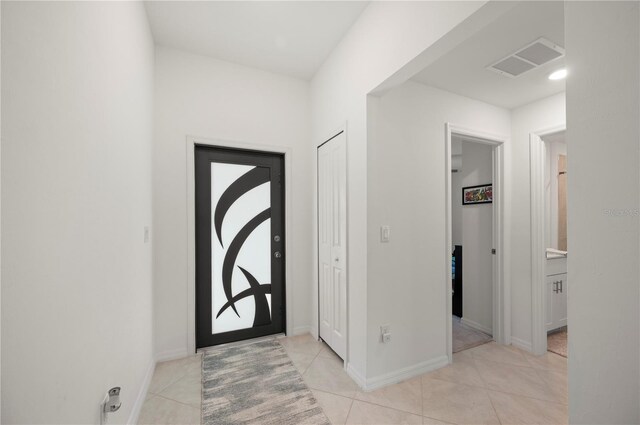 foyer entrance with light tile patterned floors and baseboards