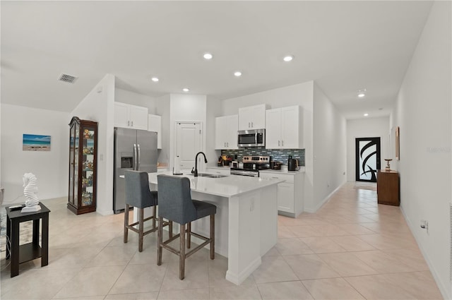 kitchen featuring stainless steel appliances, a sink, a breakfast bar, backsplash, and light tile patterned floors