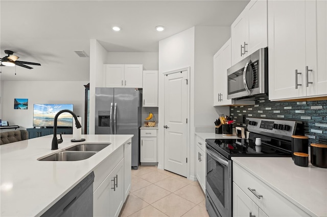 kitchen with stainless steel appliances, a sink, light countertops, tasteful backsplash, and light tile patterned flooring