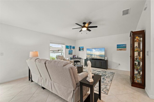 living area featuring ceiling fan, light tile patterned floors, and baseboards