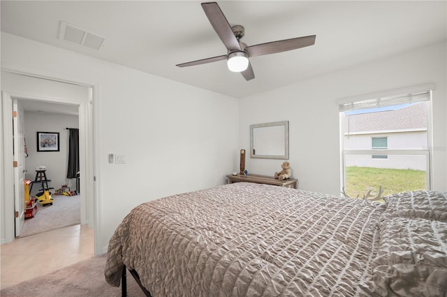 bedroom with light carpet, light tile patterned floors, and a ceiling fan