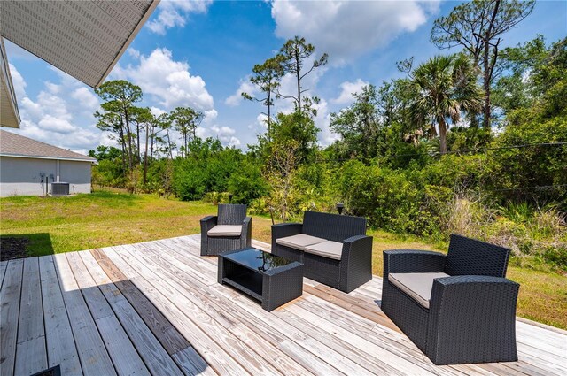 deck with an outdoor living space, a lawn, and view of wooded area
