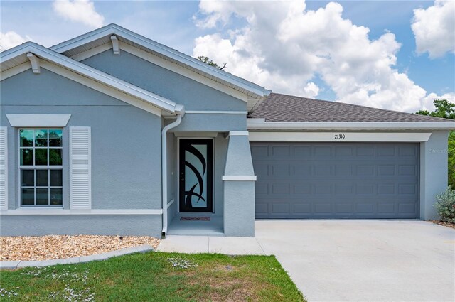 single story home with a garage, stucco siding, driveway, and roof with shingles