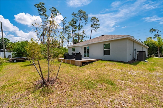 rear view of property featuring stucco siding, central air condition unit, and a lawn