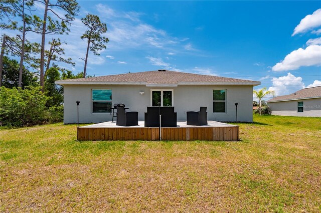 rear view of property with stucco siding and a yard