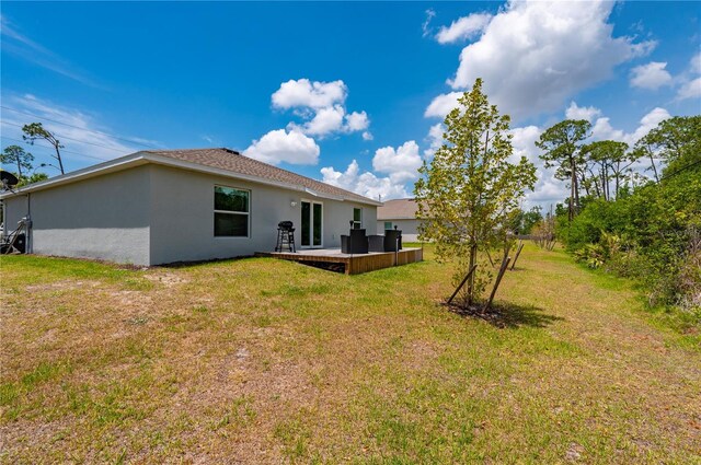 rear view of property featuring stucco siding, a lawn, and a patio