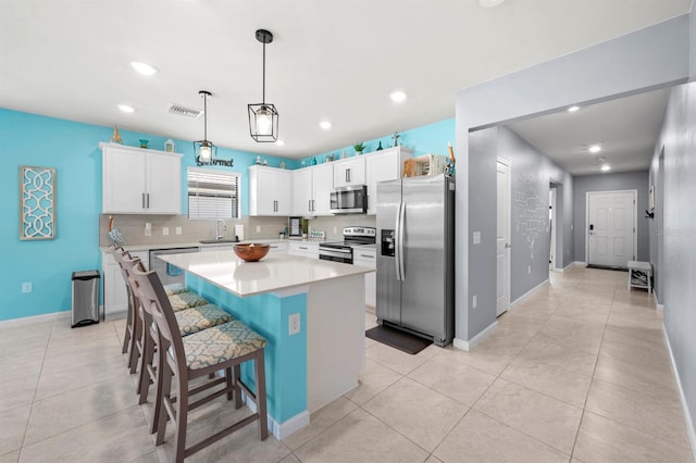 16016 Shoebutton Ct, North Fort Myers, FL 33917 - kitchen featuring appliances with stainless steel finishes, a center island, light countertops, baseboards, and white cabinetry