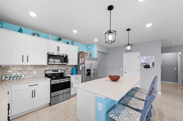 16016 Shoebutton Ct, North Fort Myers, FL 33917 - kitchen with light countertops, a center island, stainless steel appliances, white cabinetry, and decorative backsplash