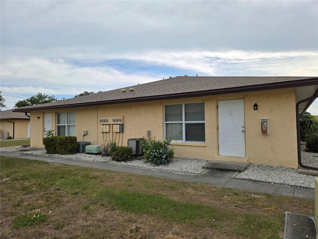 21150 Gertrude Ave Unit I3, Port Charlotte, FL 33952 - rear view of house featuring stucco siding, central AC unit, and a yard