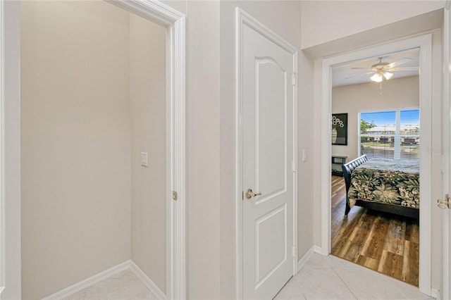 corridor featuring baseboards and light tile patterned floors
