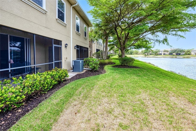 view of green lawn featuring a water view and central AC unit