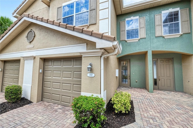 view of front of house featuring stucco siding, decorative driveway, and a garage