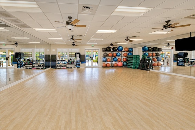 exercise room with healthy amount of natural light, wood finished floors, a paneled ceiling, and ceiling fan
